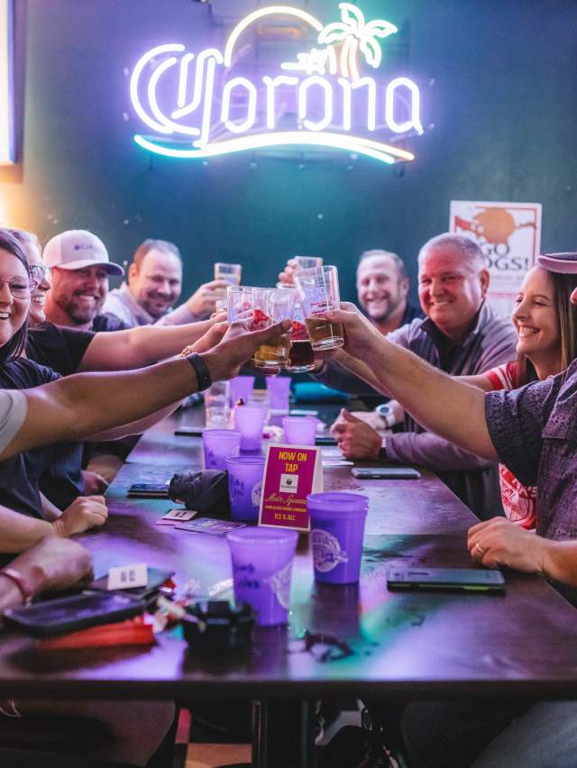 A group of friends say "Cheers!" with beverages in hand at Papas Pub in Fort Smith, Arkansas.