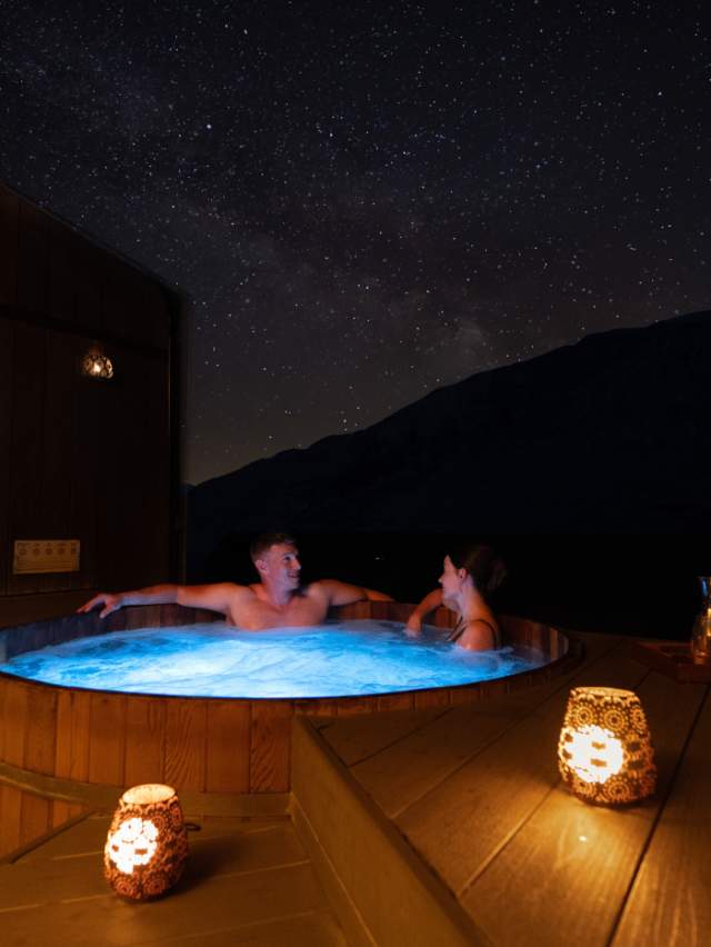 A couple enjoy a private spa at Onsen Hot Pools in Arthurs Point on a clear night