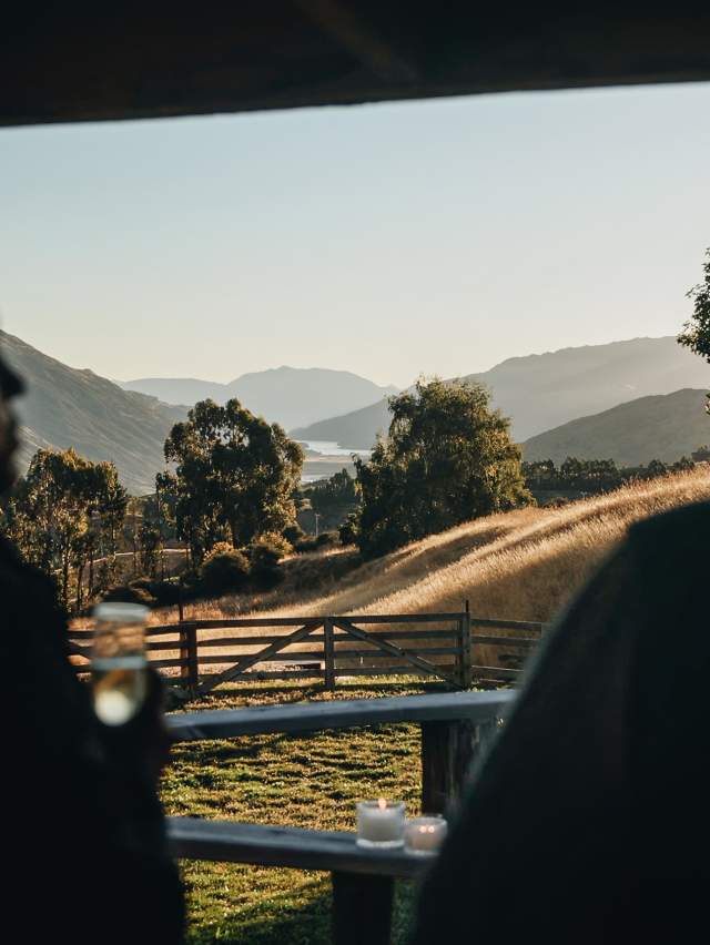 Siluete of two people talking and drinking champagne with rolling hills and sunset in the focus