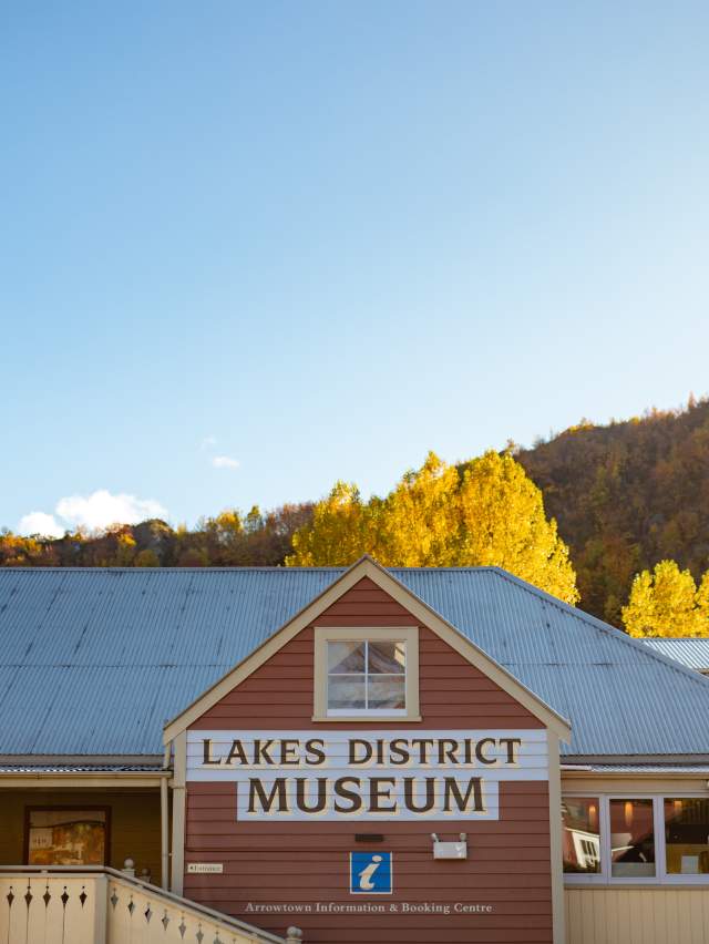A historic building set against a backdrop of autumn colours and blue sky