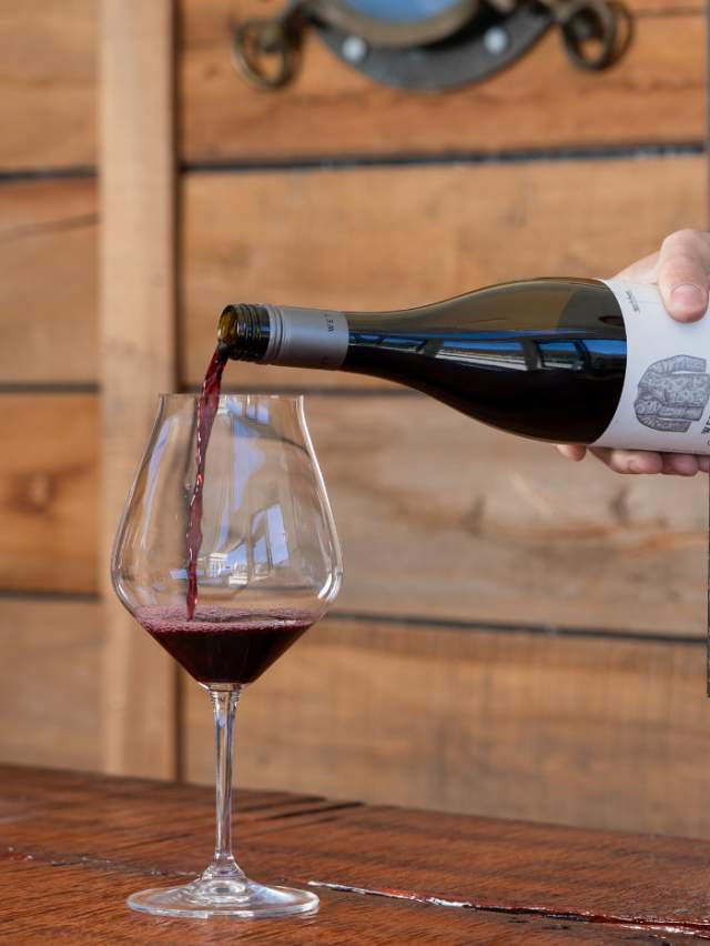 Hand pouring glass of Wet Jacket Pinot Noir
