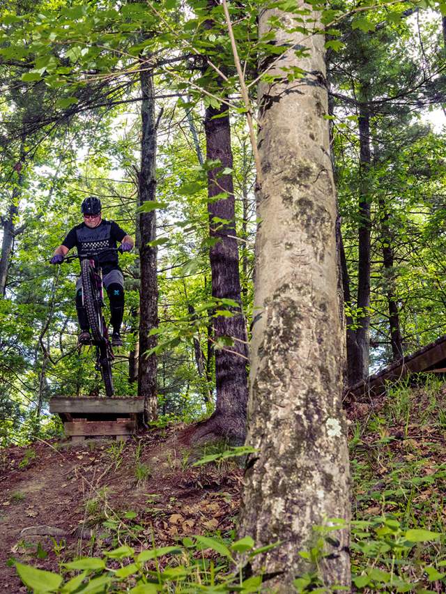 Three stunt bicyclists jumping off of ramps at Griffin Bike Park in Terre Haute, Indiana