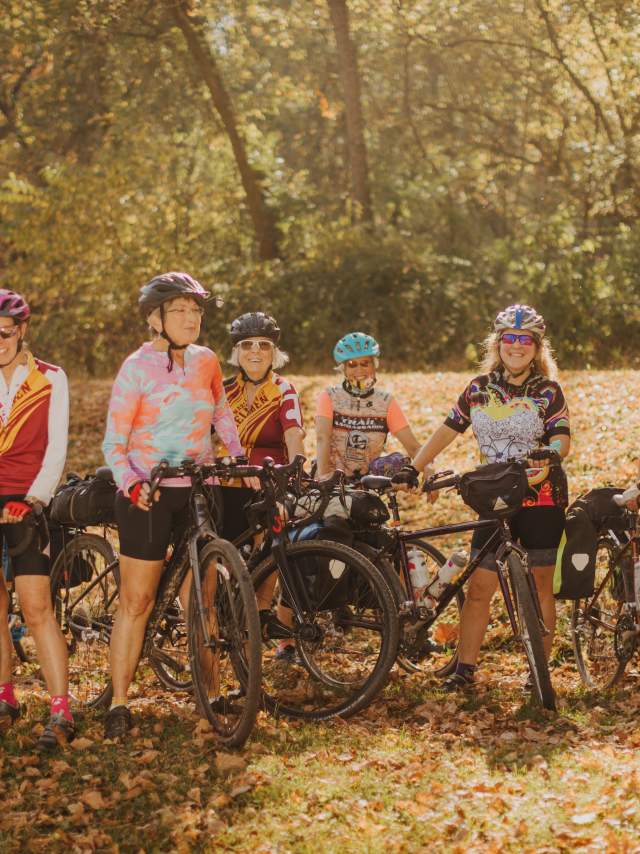 Group of women cyclists posing with their bikes along a tree-lined trail during fall in Mountain Maryland.