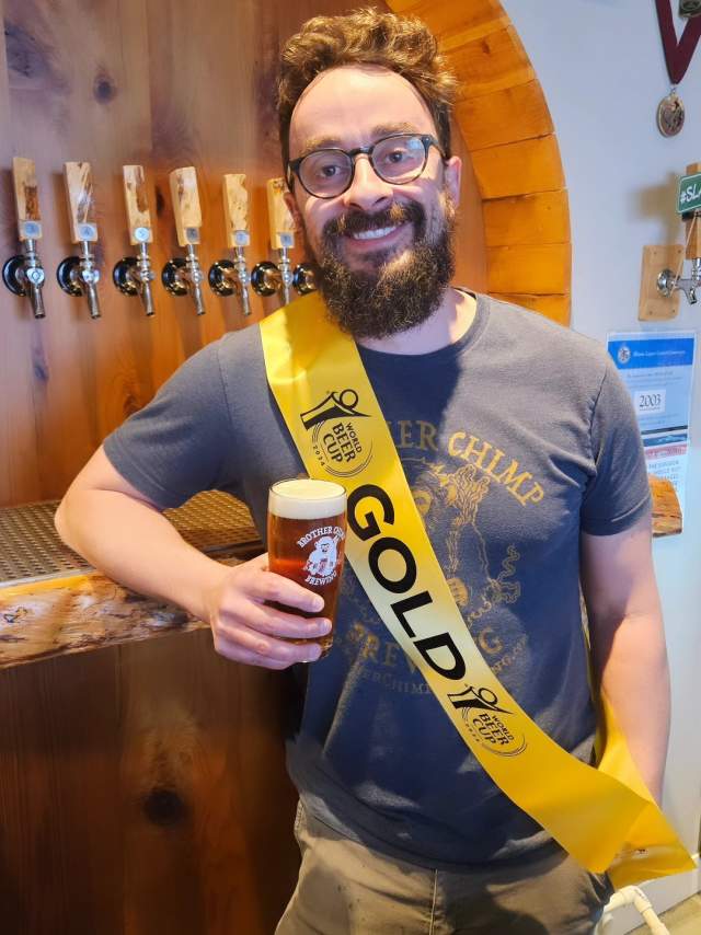 Sam Altaner, Head Brewer at Brother Chimp Brewing, poses with the brewery's 2024 Gold award winning Vienna Lager, Ludwig.