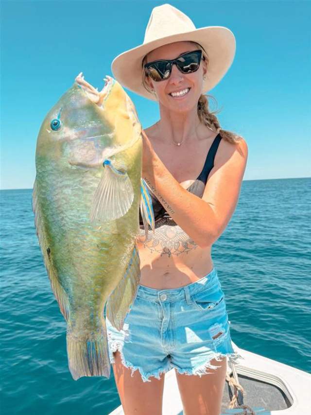 A woman in a boat holding a freshly caught Bluebone fish, in the waters off Port Hedland