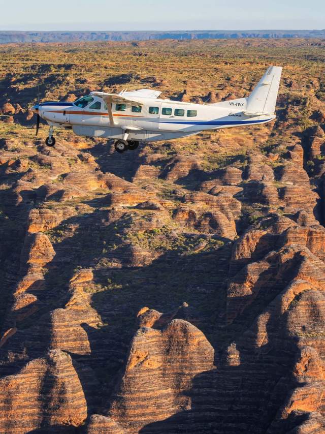 Kimberley Air Tours aircraft flying over the Bungle Bungle Range with the striped domes visible in the background