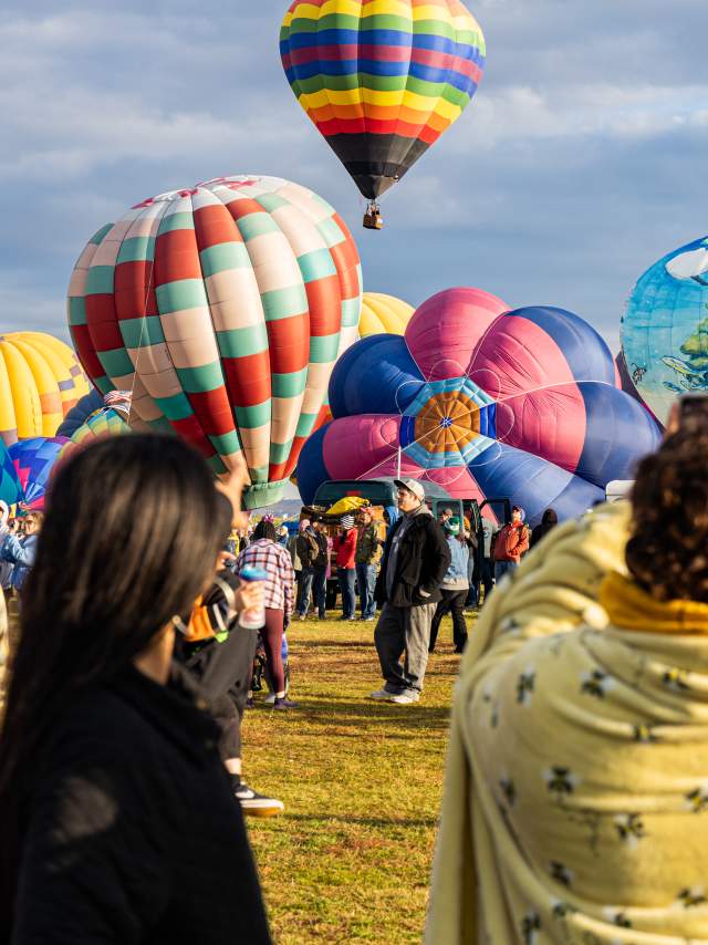 picture of hot air balloons taking flight during Balloon Fiesta with spectators watching and taking pictures