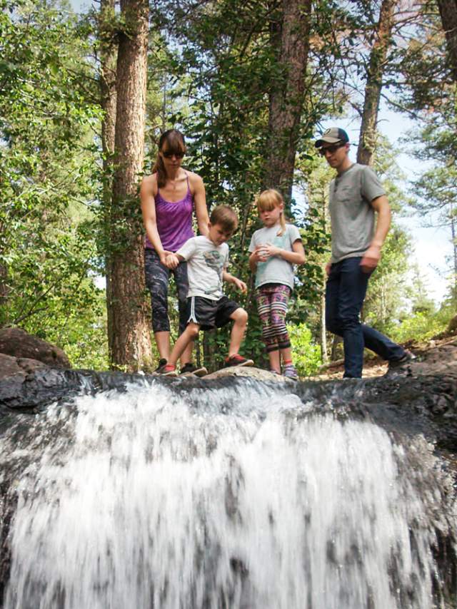 Family Of Four On Top Of A Waterfall In The Woods