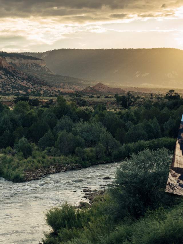 Promotional billboard for "New Mexico True Adventure Guide" featuring an individual with hoop dancing hoops, "Raise Your Spirits," with a scenic background of a winding river and mountains. In the foreground, a person is rafting on the river.