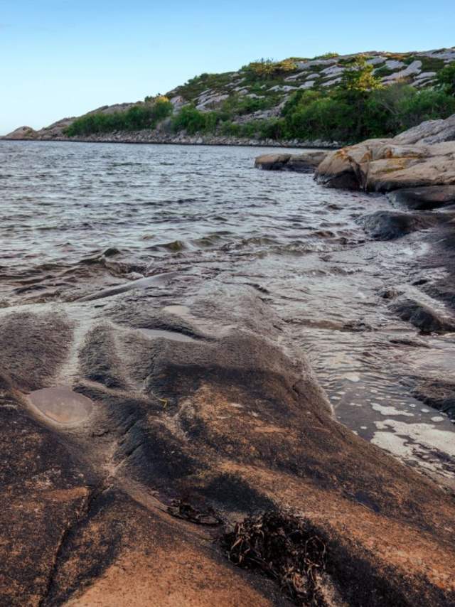 Et vann med svaberg og skog i bakgrunn