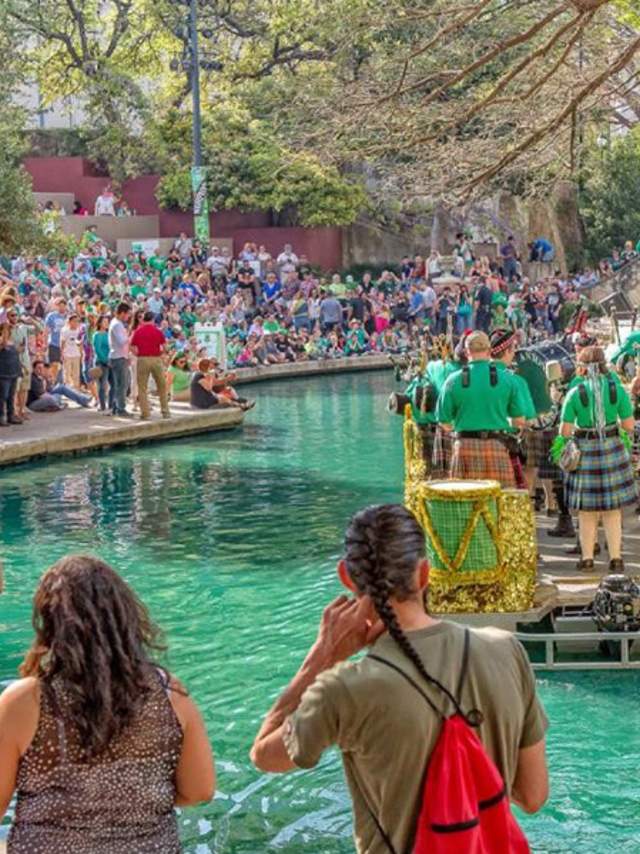 Spectators gathering around river dyed green and river barge