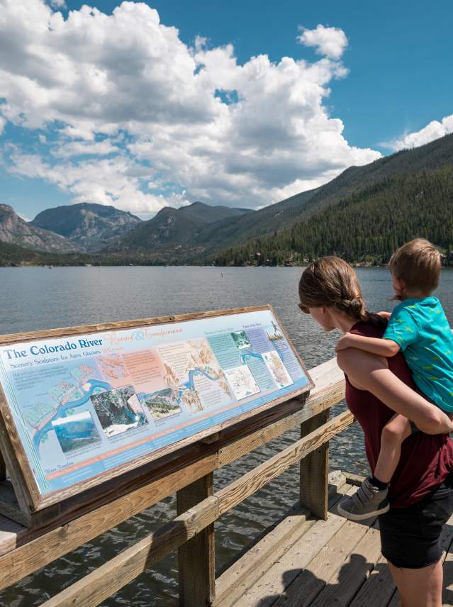 Family reading sign about the formation of Grand Lake
