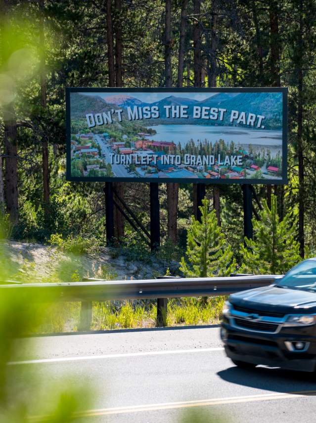 SUV drives past a billboard advertising Grand Lake that says "don't miss the best part"