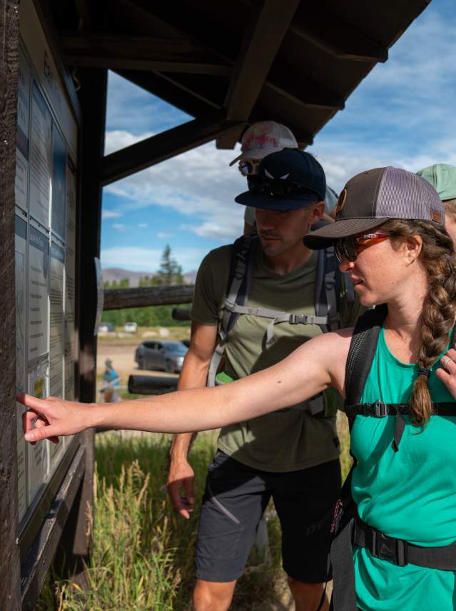 Family with young children looking at trail head map