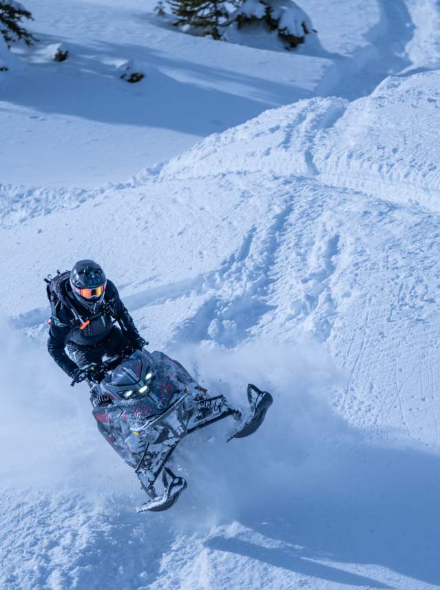 Snowmobile going over a hill in deep snow