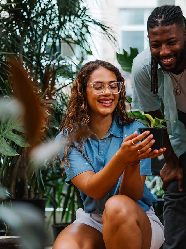 A woman smiles and show a man a potted plant at the Mason Jar Plant Shop.