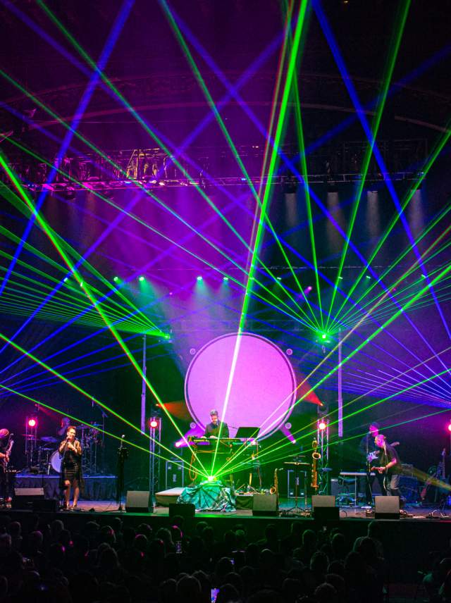 Lasers projecting from the stage while a band plays