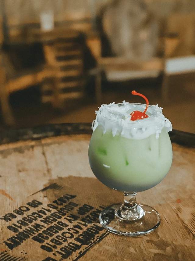 A green beverage sitting on a wooden cask