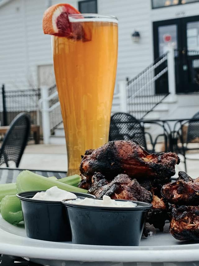 A plate of BBQ and a beer on a table outdoors