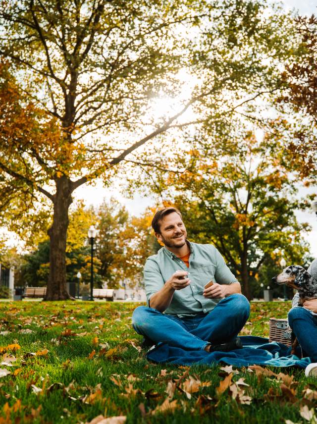 a man and woman sitting in a park eating