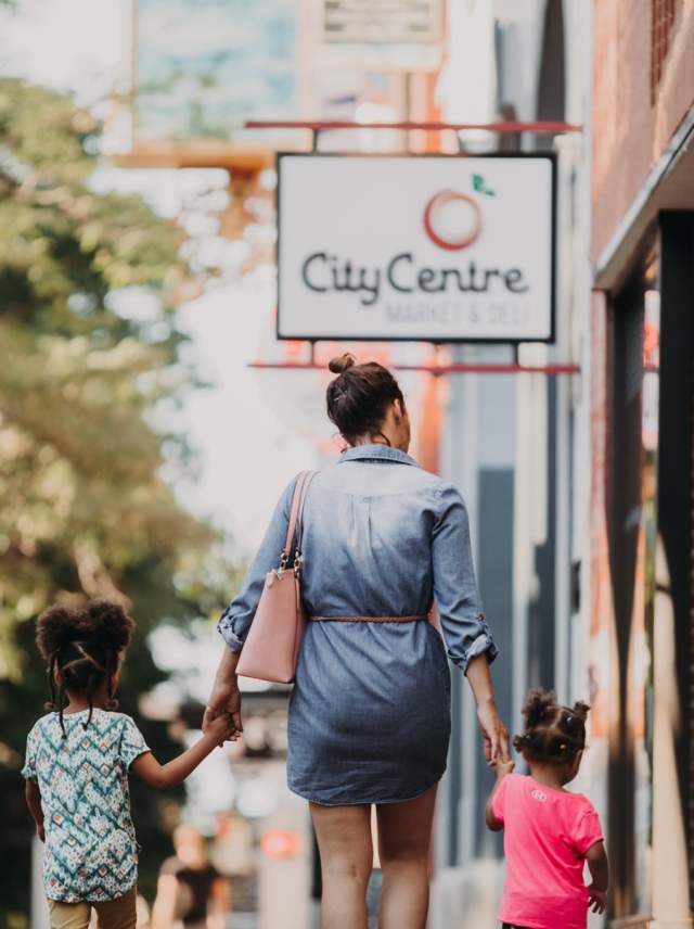 A woman and children walking in front of storefronts