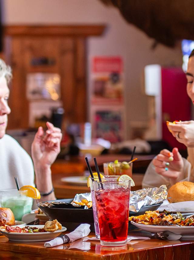 A man and three women sit at a table in Loui's Corner Bar. The table is covered in restaurant Week specials.