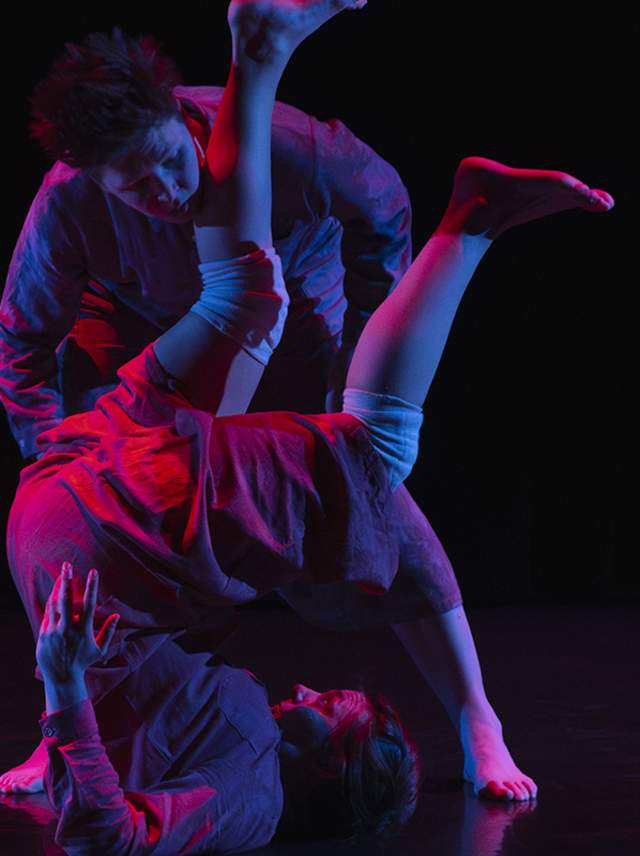 Two dancers somersault across the floor bathed in red and blue lights during RADFest.