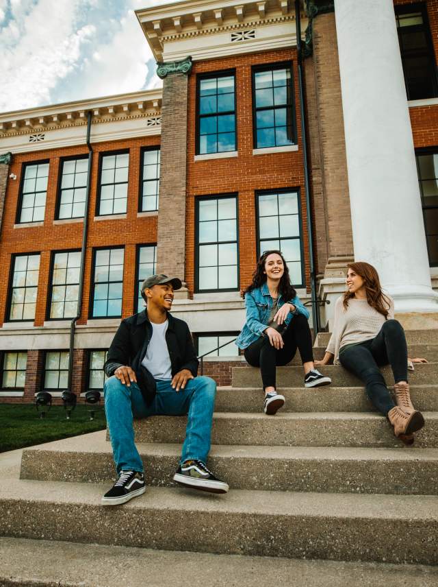 People sitting on the steps of a university building