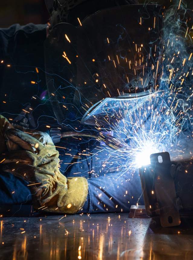 A worker in PPE welding in a shop.