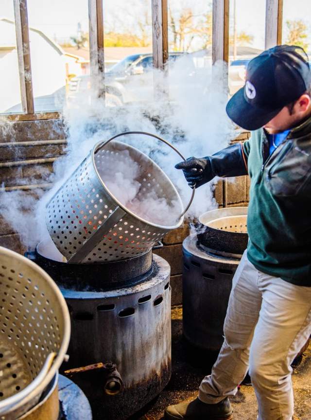 man grabbing large metal crawfish pot to place in boiling water