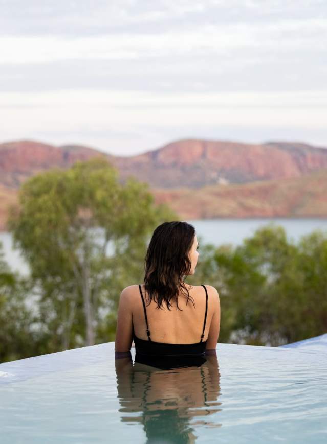 Woman in infinity swimming pool at Discovery Resorts - Lake Arygle, with a view of Lake Argyle in the background