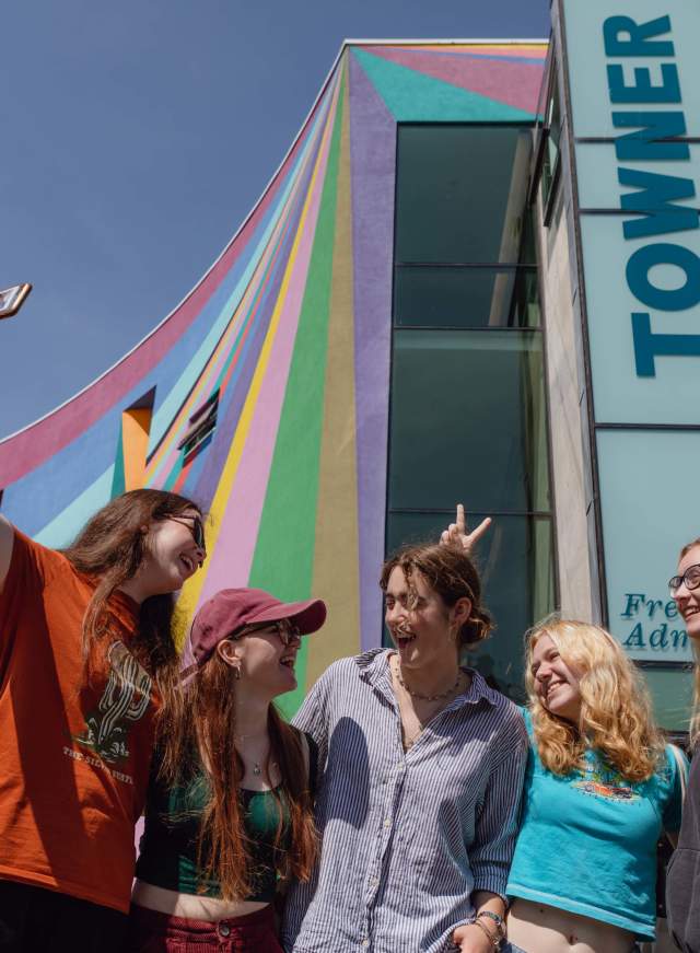 A group of young people take their photo in front of the colourful exterior of Towner gallery, Eastbourne
