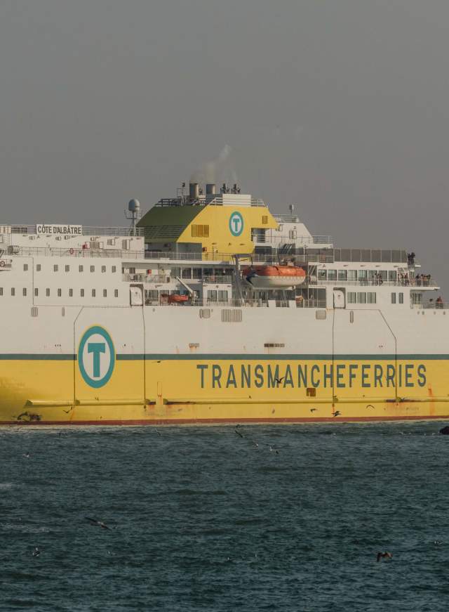 Yellow and white cross channel ferry coming in to port at Newhaven, with lighthouse in view