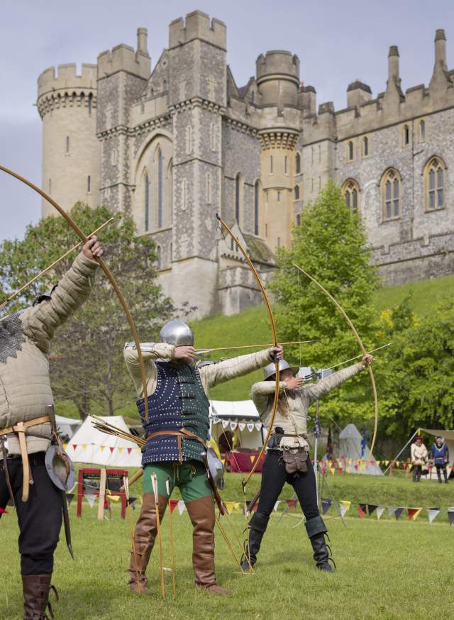 Three archers taking aim in medieval costume in the grounds of Arundel Castle in Sussex
