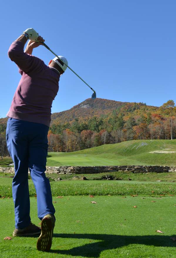 Man swinging a golf club at a golf course in Highlands, North Carolina.
