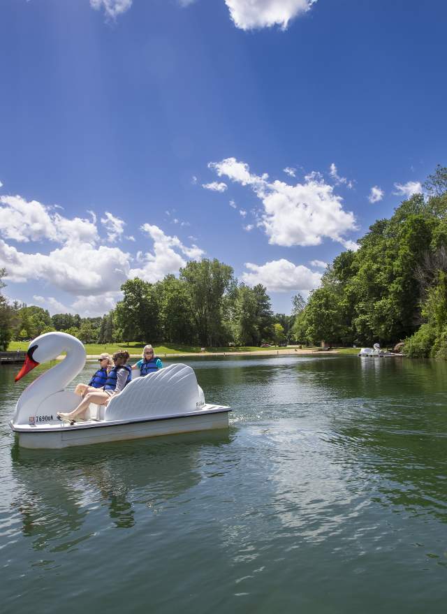 People in the swan pedal boats at the pond at Burchfield Park