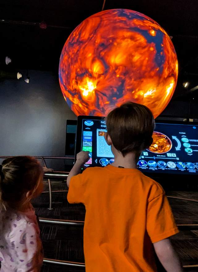 Two kids looking at a monitor of the sun in the sphere room at the MSU Museum