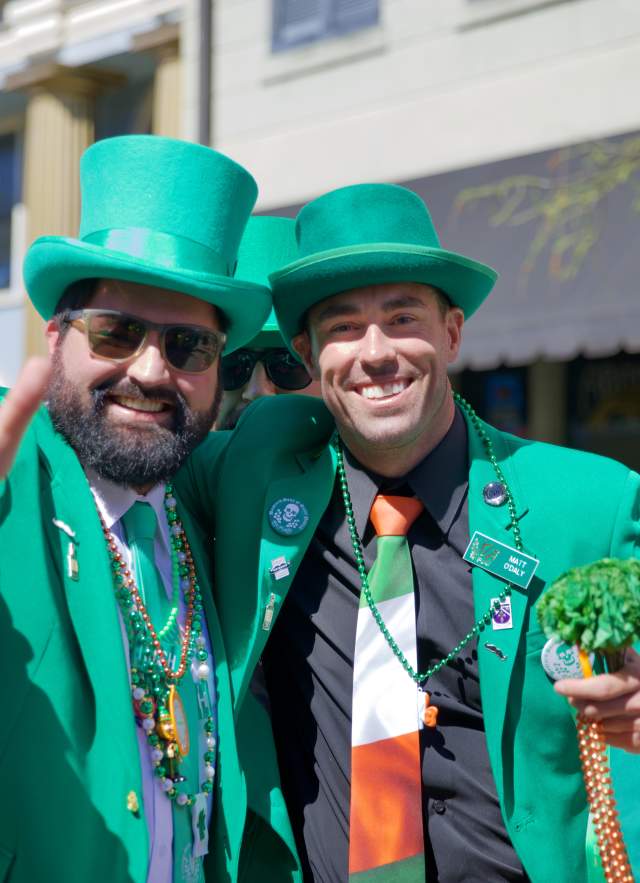 Two men wearing green and posing for a picture at a St. Patrick's Day parade