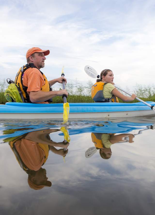 man and young girl kayaking in a blue kayak