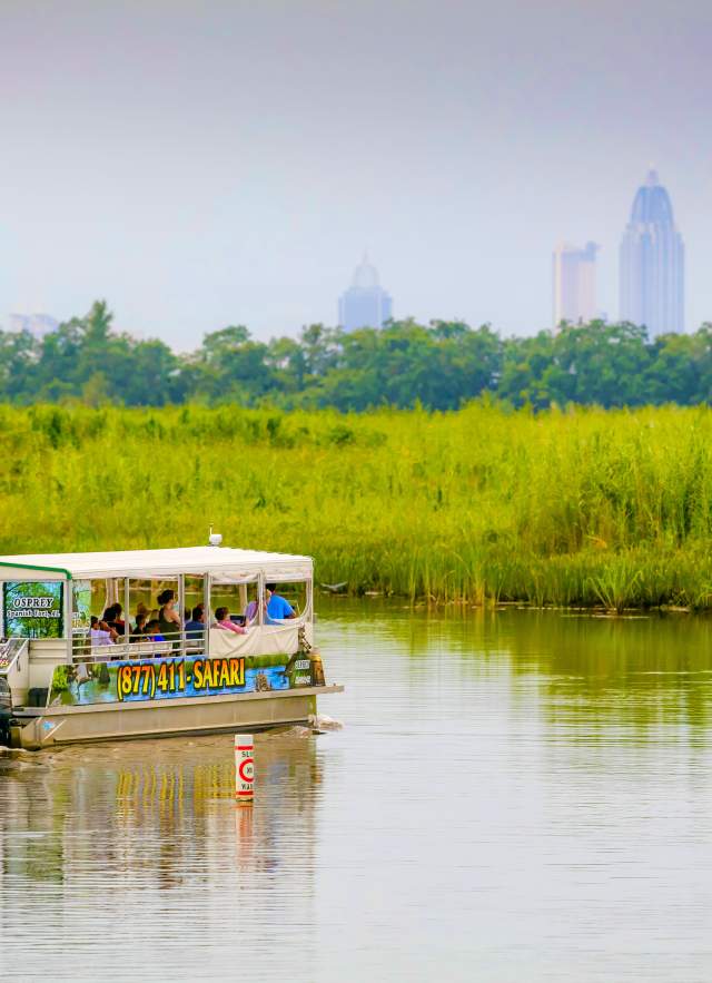 Safari tours boat in the Mobile Bay with the city in the background