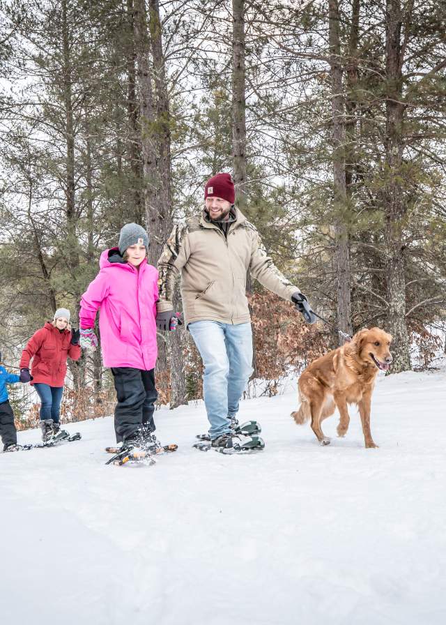 family and dog on a snowshoe trail