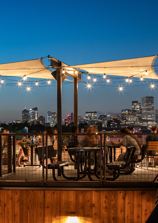 People sitting on the rooftop of BurnDown and enjoying the Denver skyline in twilight.