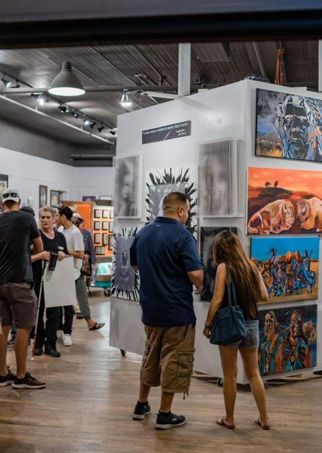 People gaze at paintings displayed in a gallery at at First Friday art walk