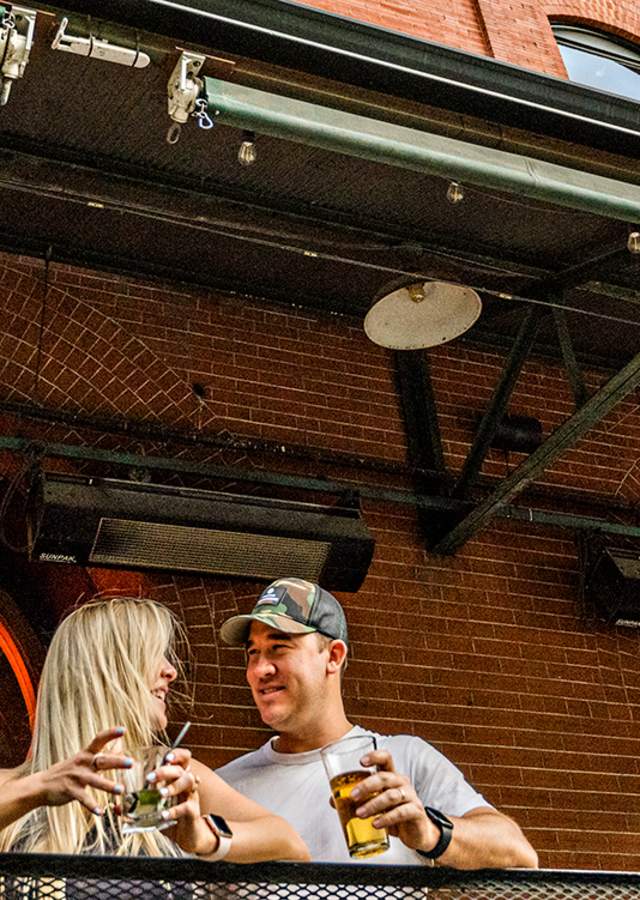 A couple stands outside Wynkoop Brewing Company's brick facade in Denver, Colorado.