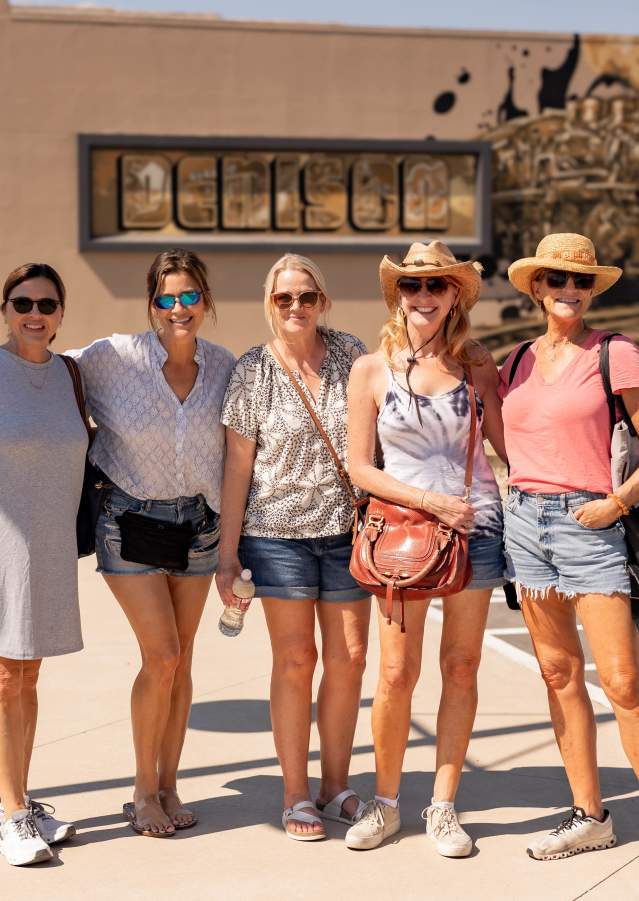 Group of friends posing in front of a colorful Denison mural downtown