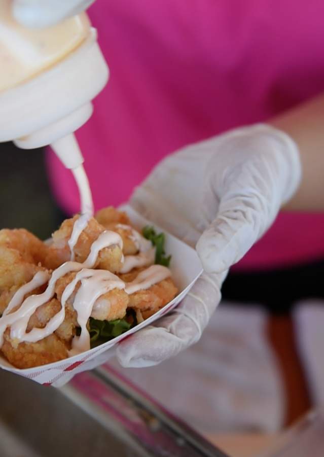 Person pouring sauce on food at the Outer Banks Seafood Festival