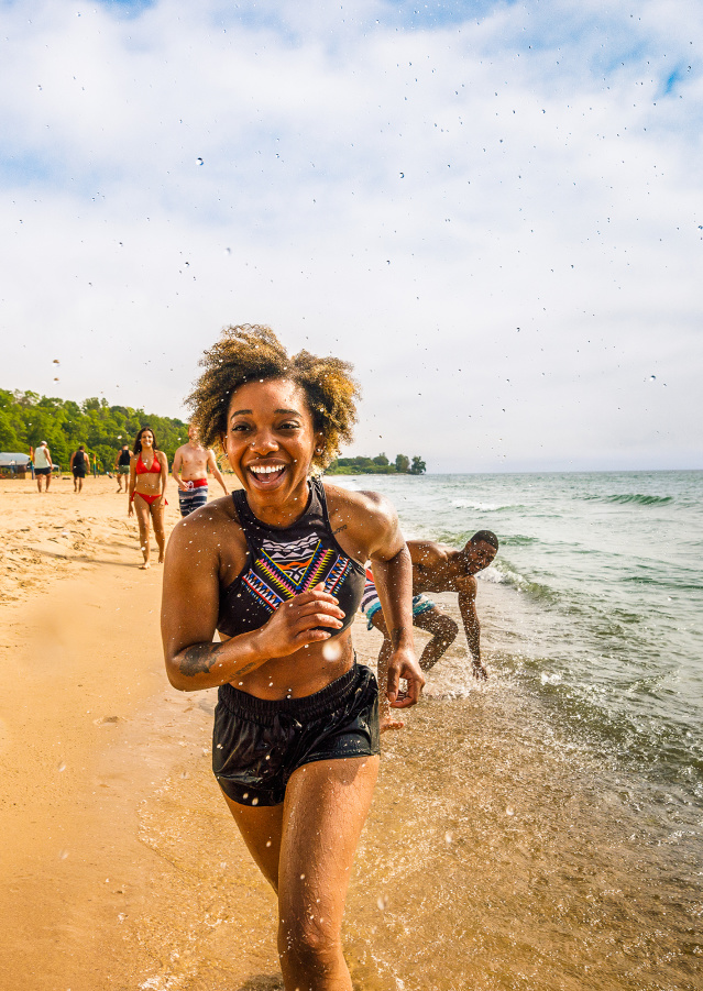 girl running on the beach with her friends following behind