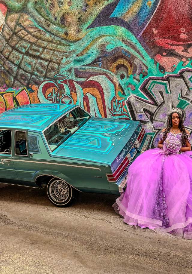 Posing for a Quinceneara photo in front of a mural.