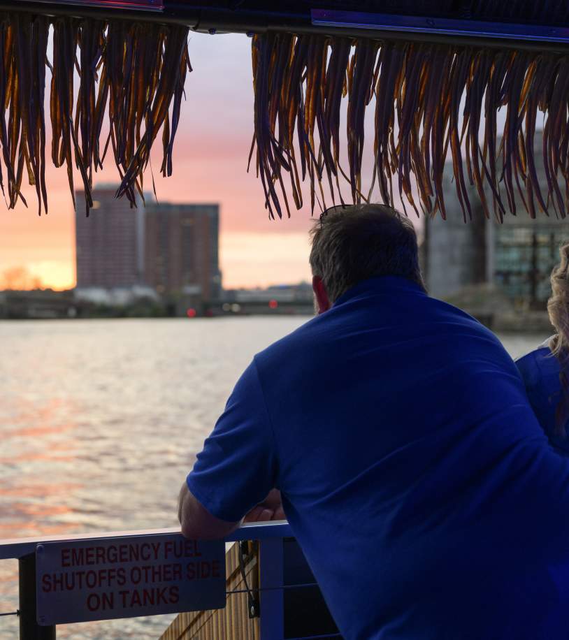 Man and woman looking out over the riverfront at sunset