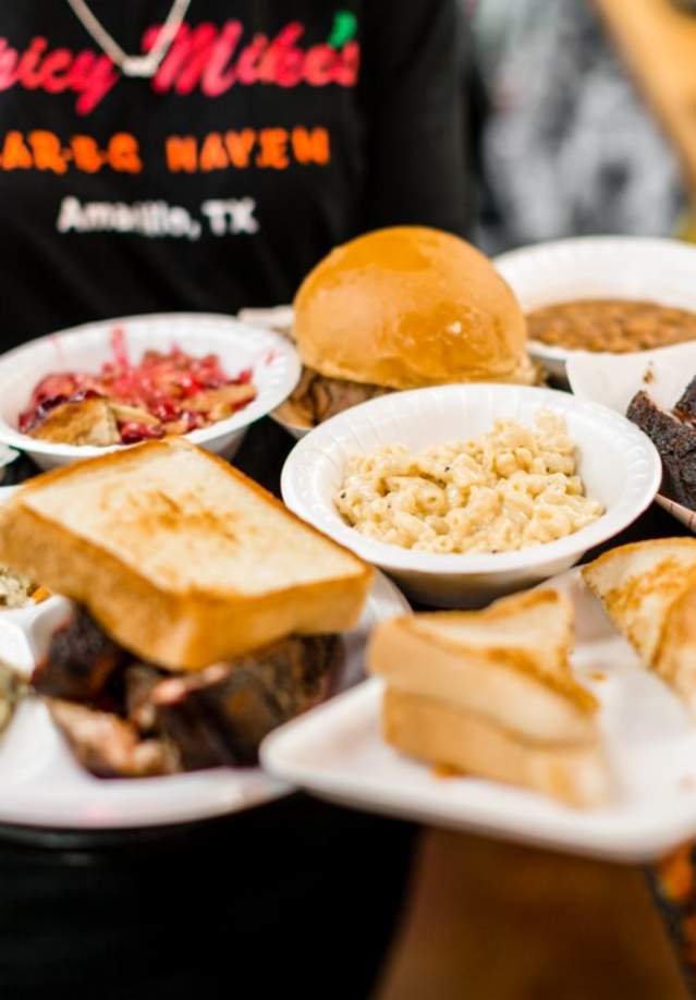 multiple different dishes of texan barbeque being served by a waitress